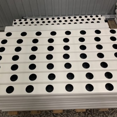 Placas brancas com furos pretos empilhadas no chão sobre pallet