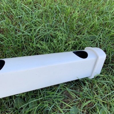 Barra branca de plástico com aberturas pretas numa relva verde