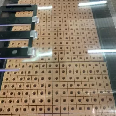 Máquina perfuradora com blocos de madeira quadrados e buracos circulares uniformes