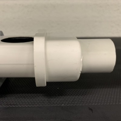 Peça tubular branca com anel circular sobre superfície preta texturizada