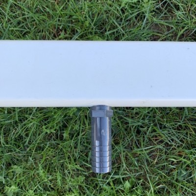 Objeto branco com conector cinza escuro sobre relva verde