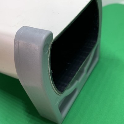 Suporte branco com cantos cinza e interior escuro sobre fundo verde