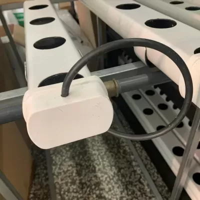 Estrutura para plantação hidropónica em tubos brancos e metal cinza com cabo preto