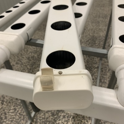 Sistema de tubos brancos para hidroponia com orifícios circulares e estrutura metálica de suporte