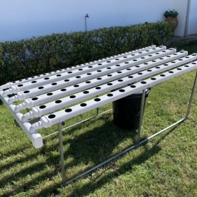 Estrutura metálica com tubos brancos perfurados para plantas no jardim