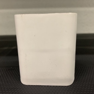 Recipiente branco retangular colocado numa superfície preta texturizada