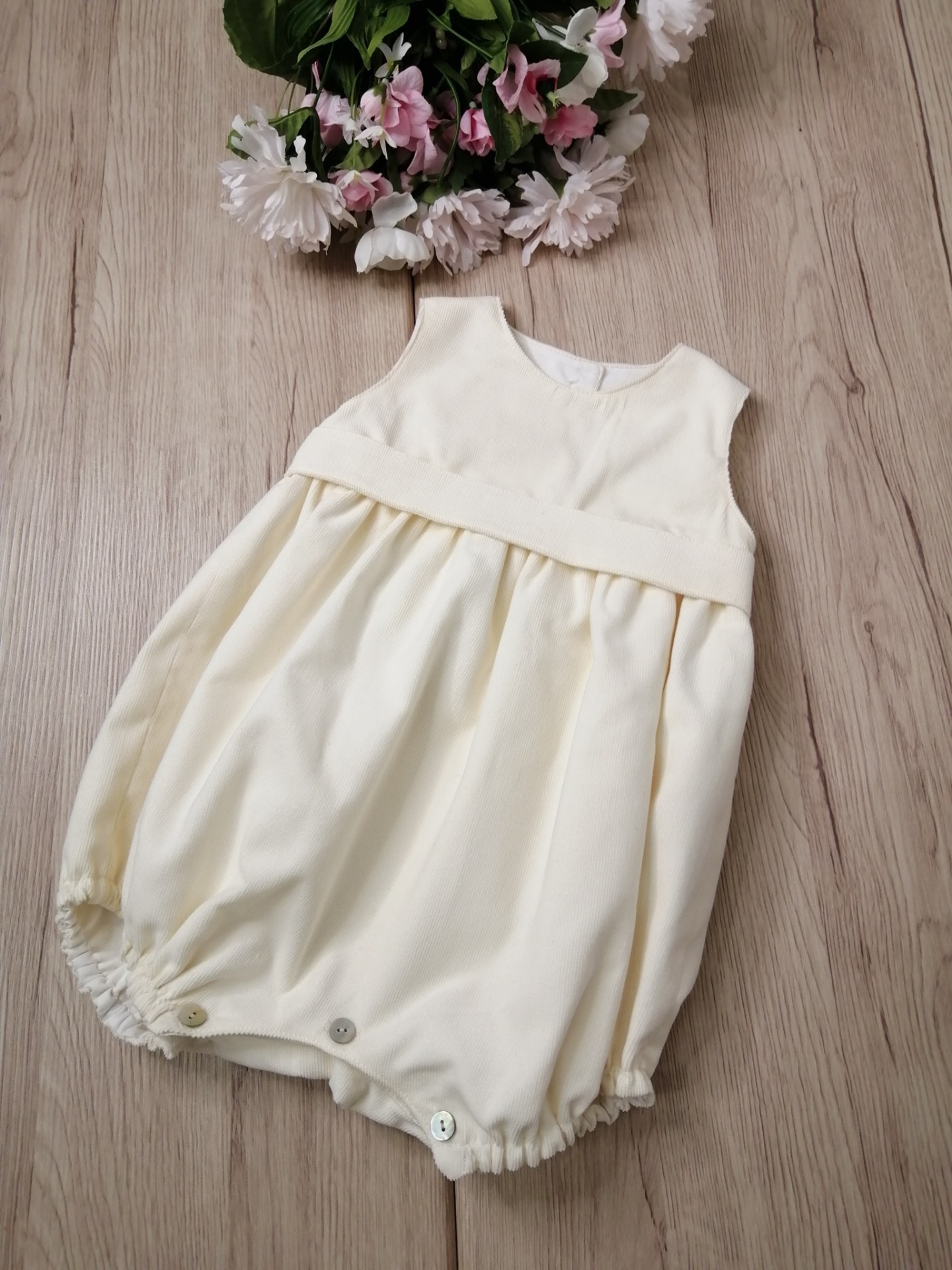 FOFO VELUDO COTELET PÉROLA Macacão de bebé creme com botões e flores ao fundo