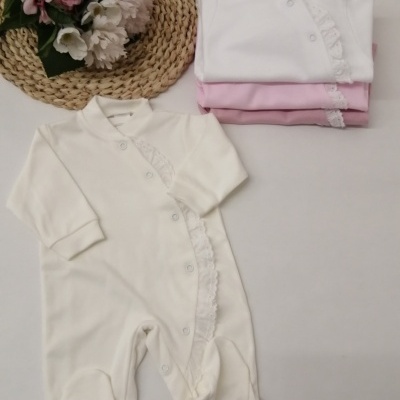 Macacão de bebé branco com rendilhado, dobrado e em exposição com outros macacões em rosa e branco