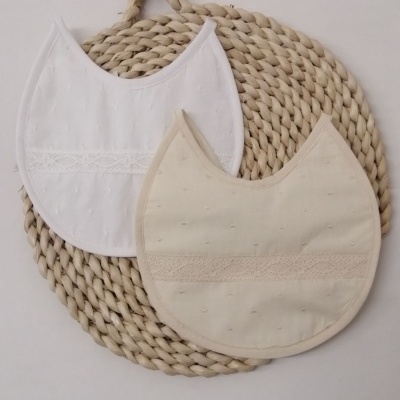 Dois babetes branco e bege claro sobre base trançada circular