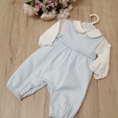 Macacão de bebé azul clara riscada de branco com parte superior branca e gola redonda, pendurado num cabide branco sobre madeira clara