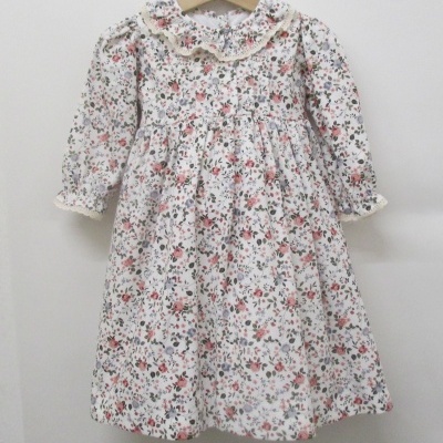 Vestido infantil floral branco com mangas compridas pendurado num cabide