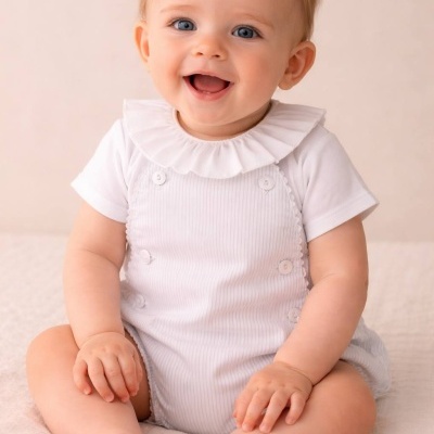 Bebé com fato de banho branco com botões sentado em tecido bege claro