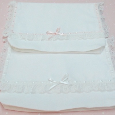 Fraldas ou toalhas brancas com renda e laços sobre tecido rosa com bolinhas brancas