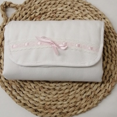 Mala branca de tecido com fita rosa sobre base redonda entrelaçada