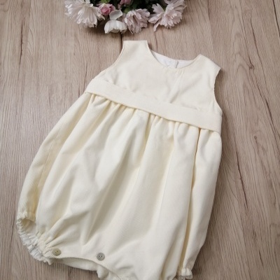 Macacão de bebé creme com botões e flores ao fundo