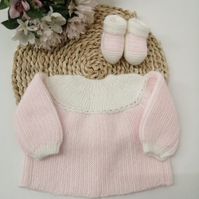 Conjunto de bebé em malha rosa e branco com botins e flores artificiais ao lado