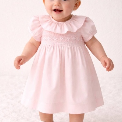 Bebé com vestido cor-de-rosa e sapatos brancos