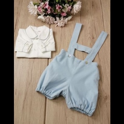 Conjunto de roupa de bebé branco e azul claro sobre madeira com flores