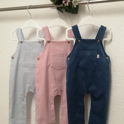 Três jardineiras para bebé azul claro, rosa e azul escuro penduradas numa barra metálica com flores decorativas