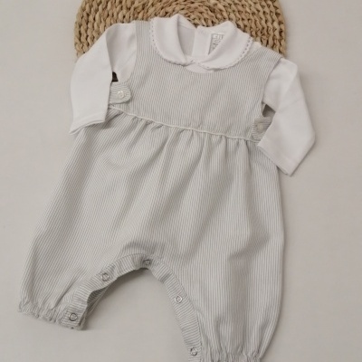 Macacão de bebé branco e cinza com gola e botões, sobre base de vime