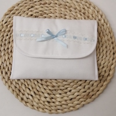 Necessaire branca com laço azul claro sobre suporte redondo de tramas grossas.