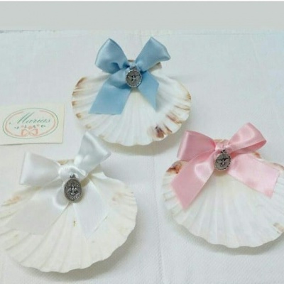 Três conchas brancas decorativas com laços coloridos e medalhas metálicas