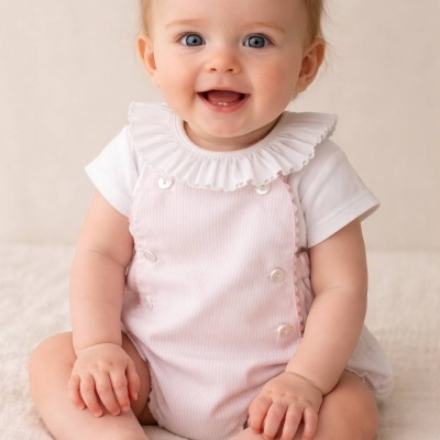 Bebé com body branco e macacão rosa claro com folhos sentado