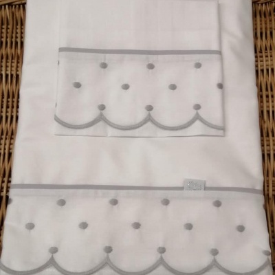 Conjunto de roupa de cama branca com padrão cinza em superfície de rattan