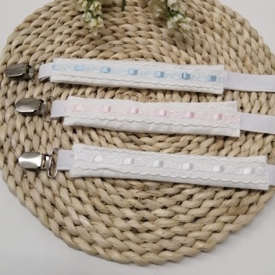 Três tiras elásticas com clipes metálicos e fitas decorativas em azul, rosa e branco sobre base trançada de fibra natural