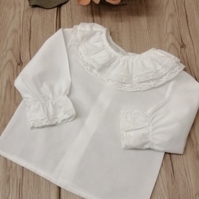 Camisola branca para criança com pontos de renda na gola e punhos