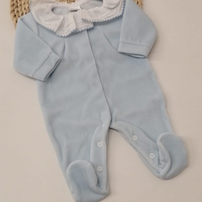 Pijama azul claro de bebé com gola branca e detalhes em tecido sobre fundo branco e tapete de palha