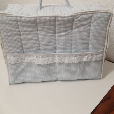 Bolsa almofadada azul claro com padrão xadrez e renda branca num ambiente interior