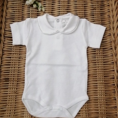 Body branco para bebé com gola peter pan sobre superfície de rattan