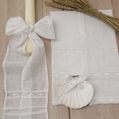 Vela branca com laço de tecido, toalha branca bordada, concha com laço, ramo de trigo seco