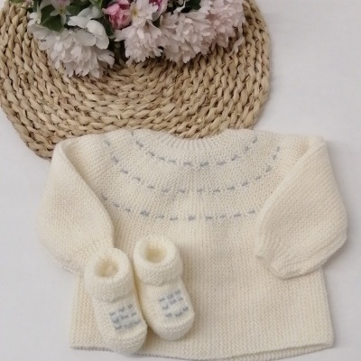 Conjunto de bebé em tricot creme com flores sobre fundo branco