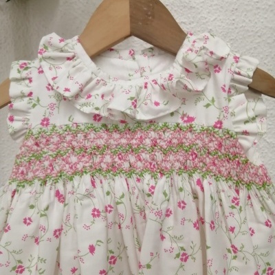 Vestido de bebé branco com padrão floral rosa e verde, com gola franzida e bordado no peito