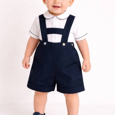 Menino com camisa branca, calção preto com alças e sapatos pretos em fundo branco