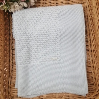 Manta de bebé azul clara em cesta de vime com flores.