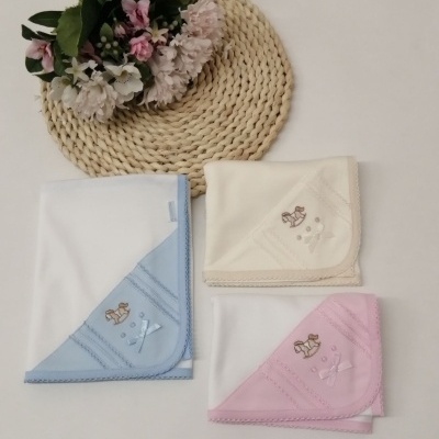 Mantas de bebé brancas com cantos coloridos e bordados, sobre fundo claro com decoração floral