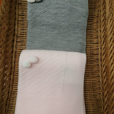 Duas mantas de malha com pompons numa cesta de verga