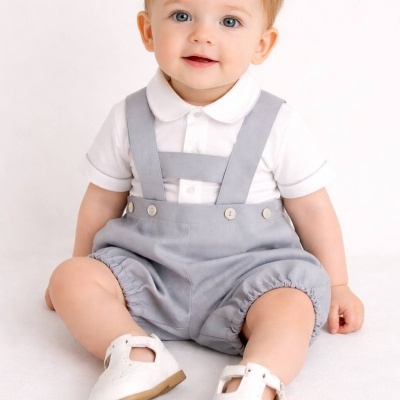 Bebé sentado com roupa branca e cinzenta e sapatos brancos