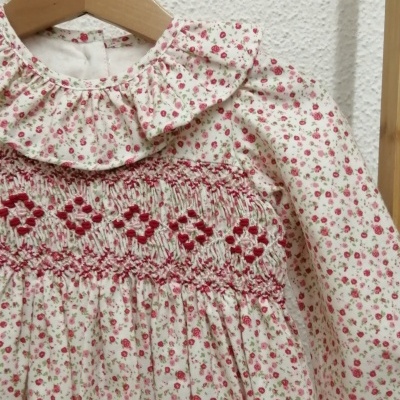 Vestido de criança com padrão floral rosa e vermelho e folho na gola