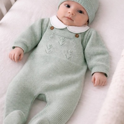 Bebé de roupa verde-água em berço branco