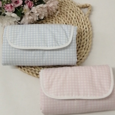 Pacotes de tecido xadrez azul e rosa sobre tapete de palha com flores