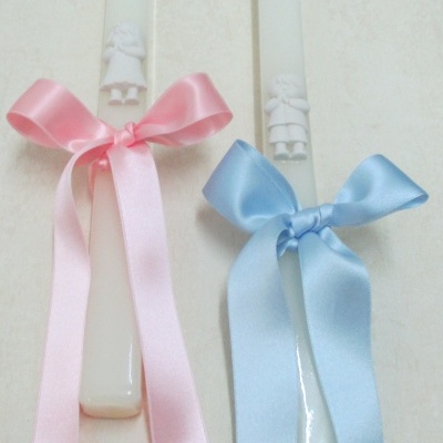 Duas velas brancas com fita cor-de-rosa e azul e figuras em relevo