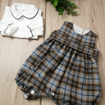 Conjunto de roupa de bebé com body branco e baba xadrez em tons azul, castanho e bege