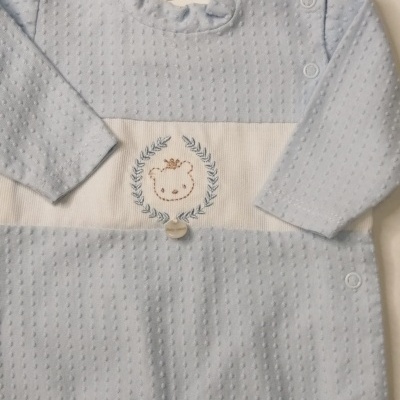 Macacão de bebé azul claro com bordado no peito e botões de pressão.