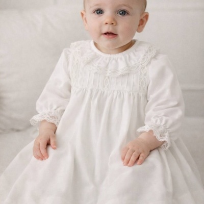 Bebé com vestido branco de manga comprida com detalhes em renda