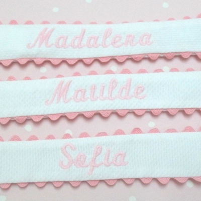 Três prendedores de chupeta rosa e branco com nomes bordados e clipes metálicos.