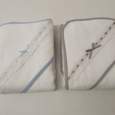 Duas toalhas de bebé brancas com bordas e laços em azul e cinzento